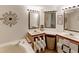 Bathroom featuring dual sinks with vanity, framed mirrors, wood-look flooring, and soaking tub at 6702 Brookridge Trl, Lakeland, FL 33810
