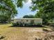 Exterior back of the home with a small deck and lush, mature landscaping at 6702 Brookridge Trl, Lakeland, FL 33810