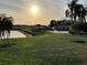 Scenic view of a well-manicured golf course with a pond and clubhouse against a sunny backdrop at 1415 Colonial Ct, Winter Haven, FL 33884