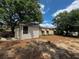 The backyard features a tan home with light-brown trim partially shaded by trees and foliage at 11407 Bobwhite Blvd, Leesburg, FL 34788