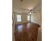 Large bedroom featuring wood-look floors, two windows with blinds, and a ceiling fan with lights at 11407 Bobwhite Blvd, Leesburg, FL 34788