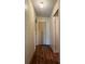 Hallway with hardwood floors, neutral-colored walls, and closed doors at 11407 Bobwhite Blvd, Leesburg, FL 34788
