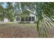 Home's exterior as seen from the backyard, featuring mature trees and simple landscaping at 30653 Pga Dr, Sorrento, FL 32776