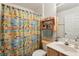 Bright bathroom featuring a colorful shower curtain and wooden shelving for storage and decorations at 30653 Pga Dr, Sorrento, FL 32776