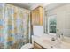 Functional bathroom with a floral shower curtain, vanity with sink, and cabinet for storage at 30653 Pga Dr, Sorrento, FL 32776