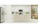Bright, all-white kitchen featuring an island with seating, modern stainless appliances, and ample storage at 703 Peroni Ave, Debary, FL 32713