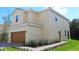 Tan two-story home boasting a two-car garage and a well-manicured lawn at 587 Bay Leaf Dr, Poinciana, FL 34759