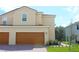 Beige two-story home featuring a two-car garage and a red tile roof at 587 Bay Leaf Dr, Poinciana, FL 34759