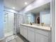 Well-lit bathroom featuring a double vanity with neutral countertops and a walk-in shower with blue curtains at 3205 Royal Tern Dr, Winter Haven, FL 33881
