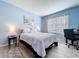 Bright bedroom featuring blue walls, a comfortable bed with a patterned comforter and wood look floors at 3205 Royal Tern Dr, Winter Haven, FL 33881
