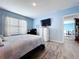 A modern bedroom featuring blue walls, a TV, workstation, and a comfortable bed with wood look flooring at 3205 Royal Tern Dr, Winter Haven, FL 33881