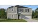 Two-story home with gray siding, black shutters, and a two-car garage is surrounded by a green lawn at 2751 Pioneer Trl, Eagle Lake, FL 33839