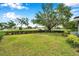 Large backyard with mature tree, green grass and border hedge and fence at 424 Forest Glen Ave, Lakeland, FL 33813