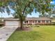 Brick home featuring a large front yard with mature trees and an expansive driveway leading to a two-car garage at 424 Forest Glen Ave, Lakeland, FL 33813