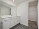 Modern bathroom featuring a large mirror, white cabinets, and gray wood-look flooring at 113 Cimarron Ln, Poinciana, FL 34759