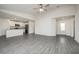Spacious living room features gray wood flooring with a view of the modern kitchen at 113 Cimarron Ln, Poinciana, FL 34759