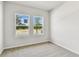 Bright bedroom with neutral carpet, two windows offering natural light, and a view of the outdoors at 6051 Sacred Oak Ave, Mount Dora, FL 32757