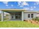 Back exterior of the home featuring a covered patio with sliding glass doors and landscaped backyard at 6051 Sacred Oak Ave, Mount Dora, FL 32757