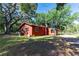Side view of red home surrounded by mature trees in large yard with covered outdoor spaces at 1836 Cr 609B, Bushnell, FL 33513