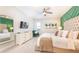 Serene main bedroom featuring a king-sized bed, ensuite bath, TV, green accent wall, and neutral decor at 7682 Fairfax Dr, Kissimmee, FL 34747