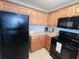 Efficient kitchen with oak cabinets, black appliances, granite counters, and tiled flooring at 13415 Blue Heron Beach Dr # 1006, Orlando, FL 32821