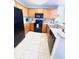 Modern kitchen with wooden cabinets, black appliances, granite counters, and tiled floors at 13415 Blue Heron Beach Dr # 1006, Orlando, FL 32821