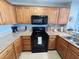 Functional kitchen features wood cabinets, black appliances, granite countertops, and a tiled floor at 13415 Blue Heron Beach Dr # 1006, Orlando, FL 32821
