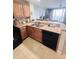 Practical kitchen featuring wooden cabinetry, granite counters, black appliances, and tiled floors at 13415 Blue Heron Beach Dr # 1006, Orlando, FL 32821