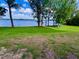Expansive green lawn meets the serene water's edge, framed by mature trees and blue skies at 13415 Blue Heron Beach Dr # 1006, Orlando, FL 32821