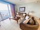 Inviting living room featuring a balcony, tile flooring, and comfortable sofas at 13415 Blue Heron Beach Dr # 1006, Orlando, FL 32821