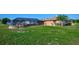 Green backyard lawn with view of screened in porch and outdoor seating at 6531 Red Grange Blvd, Indian Lake Estates, FL 33855