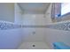 Bright bathroom featuring a shower stall with white tile surround and blue accent tile at 6531 Red Grange Blvd, Indian Lake Estates, FL 33855