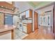 A kitchen with white appliances, wood cabinets, a breakfast bar, and white tile floors, flowing into the entryway at 6531 Red Grange Blvd, Indian Lake Estates, FL 33855