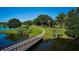 Scenic view of a serene golf course featuring a pedestrian bridge, lush greenery, and tranquil water features at 6531 Red Grange Blvd, Indian Lake Estates, FL 33855