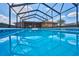 A swimming pool with clear blue water reflects the blue sky and a screened enclosure at 6531 Red Grange Blvd, Indian Lake Estates, FL 33855