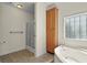 Bright bathroom featuring a soaking tub, glass-enclosed shower, tiled floors, and a linen closet at 7165 Cr 655, Bushnell, FL 33513