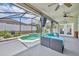 A covered pool with teal water and a gray concrete patio with blue outdoor seating and a tiki decoration at 2719 Osprey Creek Ln, Orlando, FL 32825