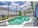 An in-ground teal swimming pool surrounded by green plants and an aluminum pool cage at 2719 Osprey Creek Ln, Orlando, FL 32825