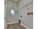 Small laundry room with wood-look floors, oval window, and shelf storage at 210 Alta Vista St, Debary, FL 32713