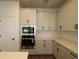 Spacious kitchen featuring built-in microwave, tile backsplash and white cabinetry at 6069 Sacred Oak Ave, Mount Dora, FL 32757
