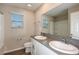 Bright bathroom featuring double vanity with gray countertop, white cabinets, and window at 1042 Foreshore Ln, Haines City, FL 33844