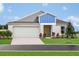 Charming single-Gathering home with a well-manicured lawn and a two-car garage on a sunny day at 1054 Foreshore Ln, Haines City, FL 33844