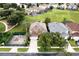 Aerial view of a home featuring a spacious driveway, lush trees, and a fenced area, nestled within a residential neighborhood at 8646 La Isla Dr, Kissimmee, FL 34747