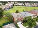 Aerial view of a two-story home with a well-maintained lawn, mature trees, and a backdrop of neighboring houses and lush greenery at 8646 La Isla Dr, Kissimmee, FL 34747