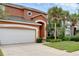 Inviting two-story home with a two-car garage, mature palm trees and a walkway at 8646 La Isla Dr, Kissimmee, FL 34747