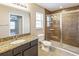 Bathroom featuring a granite countertop, tiled glass shower, and window with natural light at 1 Pecan Course Cir, Ocala, FL 34472