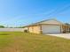 View of the house's side and two car garage with a big backyard with a white fence at 1 Pecan Course Cir, Ocala, FL 34472