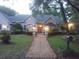 Dusk view of home with manicured lawn, brick path, landscape lighting, and mature trees at 19811 Lake Dorr Rd, Altoona, FL 32702