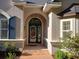 Beautiful glass-paned front door with arched entryway and well manicured landscaping at 19811 Lake Dorr Rd, Altoona, FL 32702
