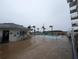 Outdoor pool area with lounge chairs, palm trees and building's exterior under a cloudy sky at 3100 Ocean Shore Blvd # 101, Ormond Beach, FL 32176